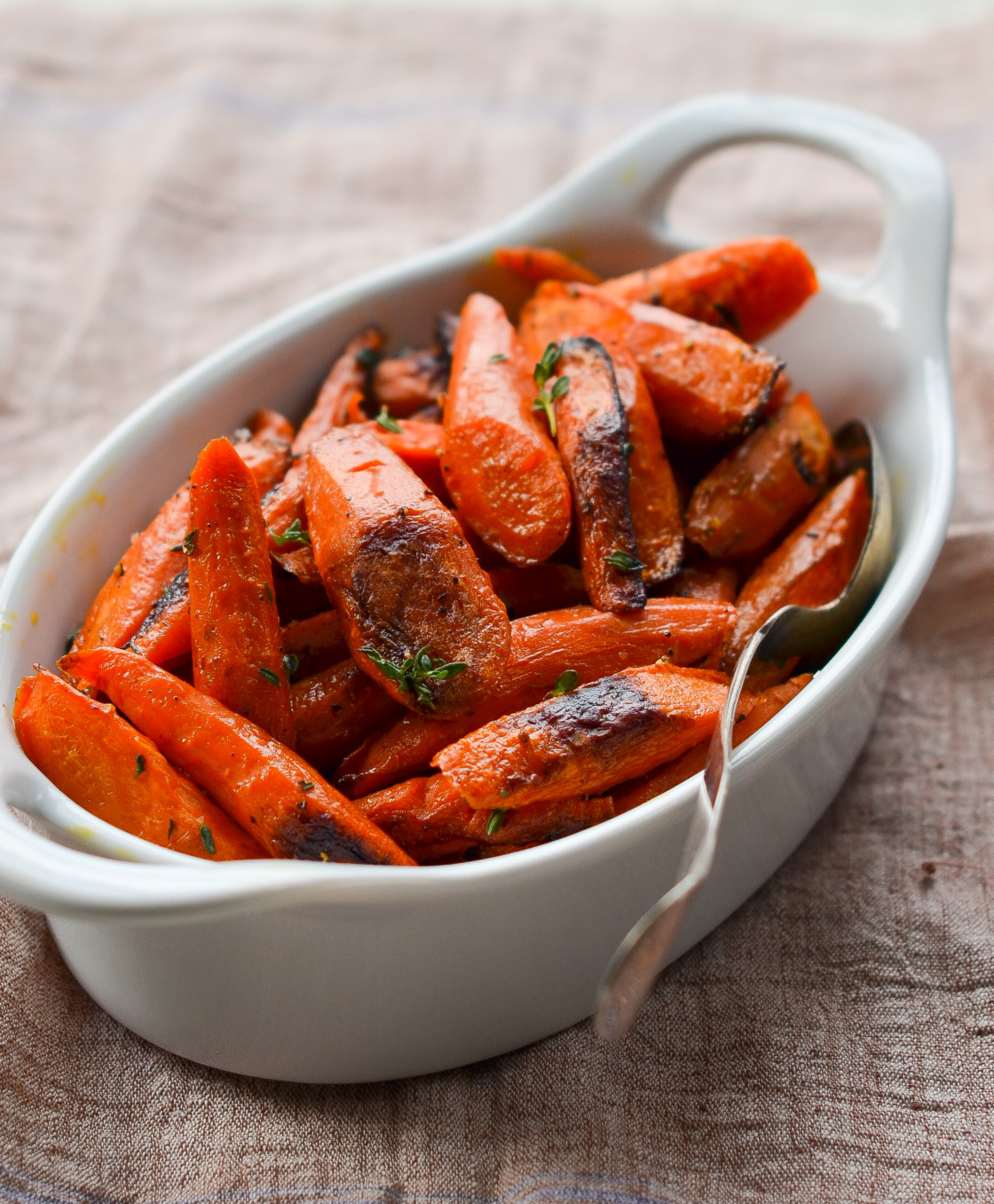 Roasted carrots with thyme in a baking dish.