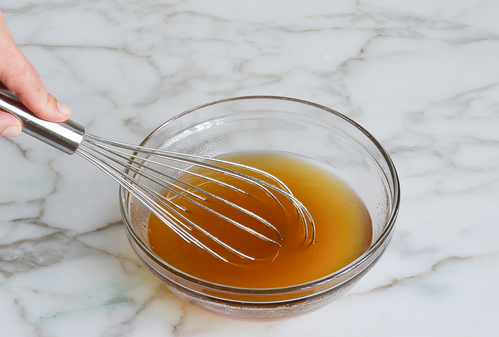 whisking honey and oil in glass mixing bowl