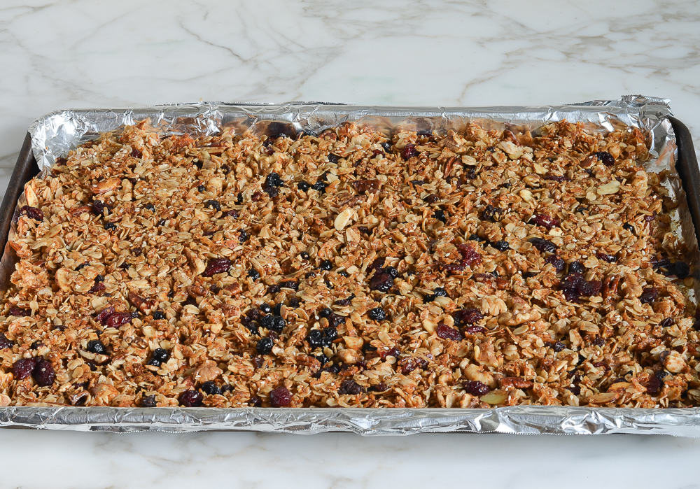 mixture after fruit has been combined and granola has been compacted on foil-lined baking sheet