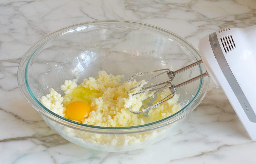 Eggs in a bowl with beaten butter and sugar.