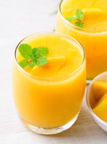 tropical peach mango smoothies in glasses garnished with fresh mint