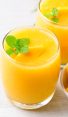 tropical peach mango smoothies in glasses garnished with fresh mint