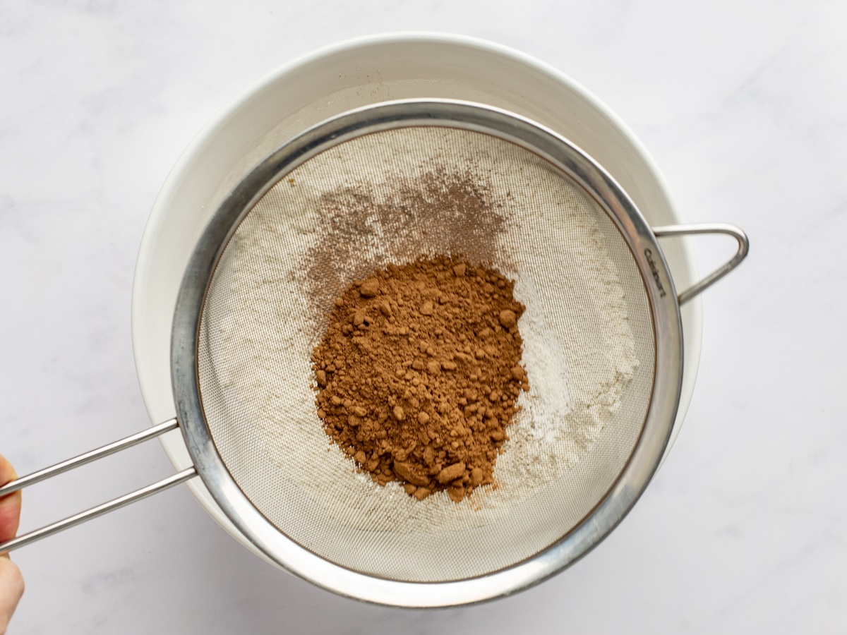 sifting cocoa powder into dry ingredients