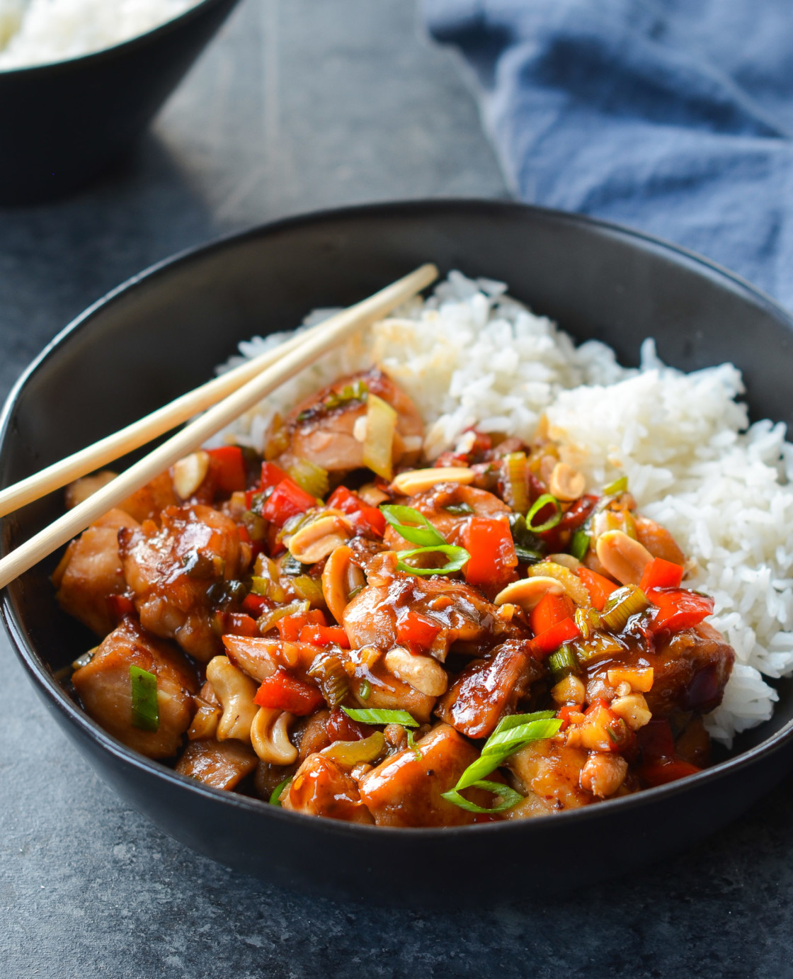 Chopsticks on a bowl of Kung Pao chicken with rice.