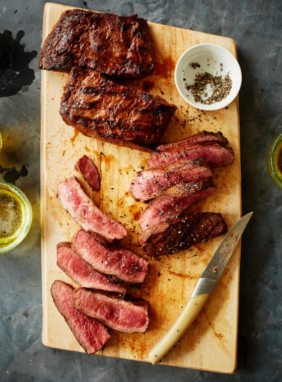 Sliced carne asada on a wooden cutting board.