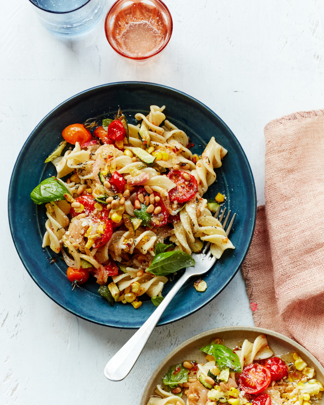 Fork on a blue plate with pasta primavera.