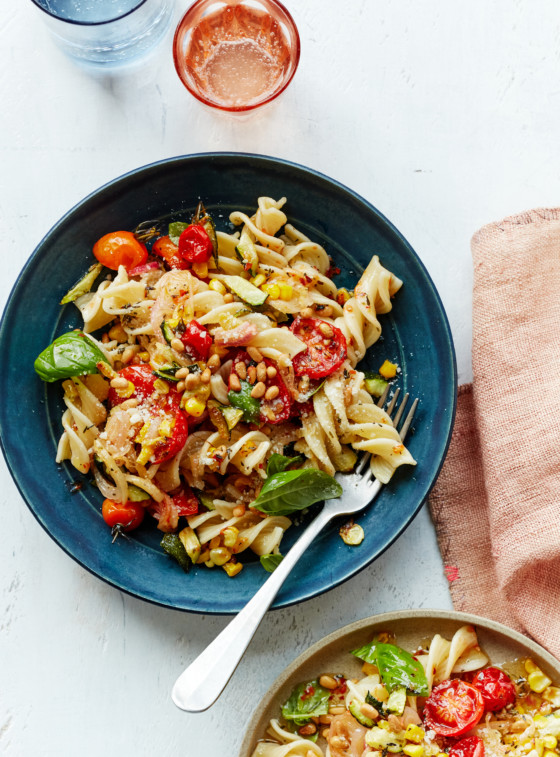 Fork on a blue plate with pasta primavera.