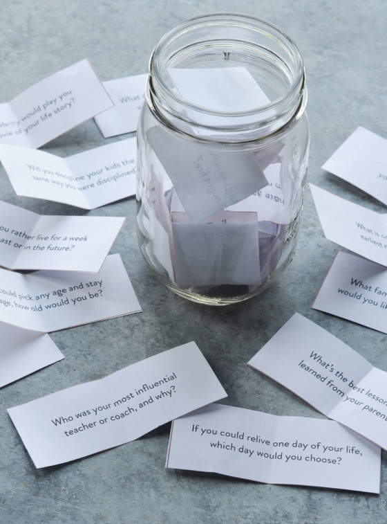 Jar surrounded by pieces of paper with questions written on them.