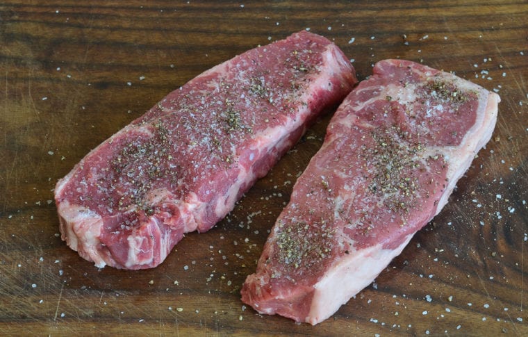 Seasoned steaks on a cutting board.
