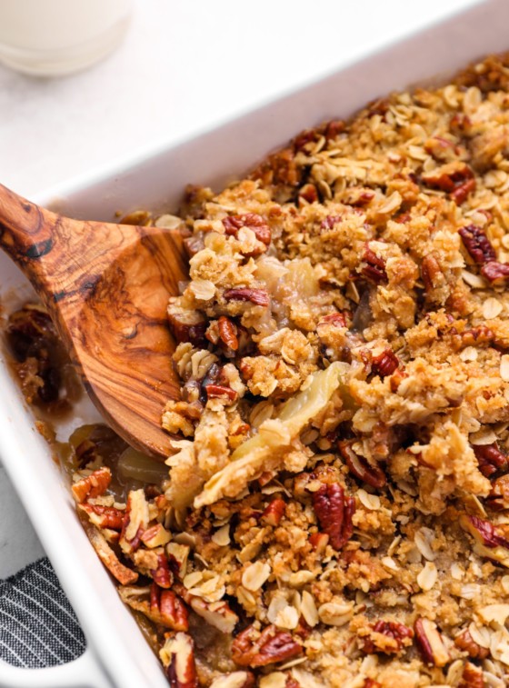 Wooden spoon serving apple crisp.