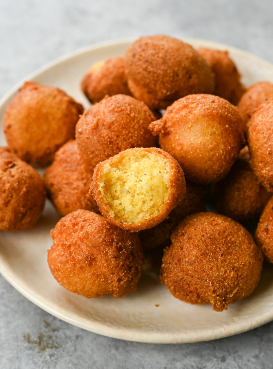 Pile of hush puppies, one of which is missing a bite.