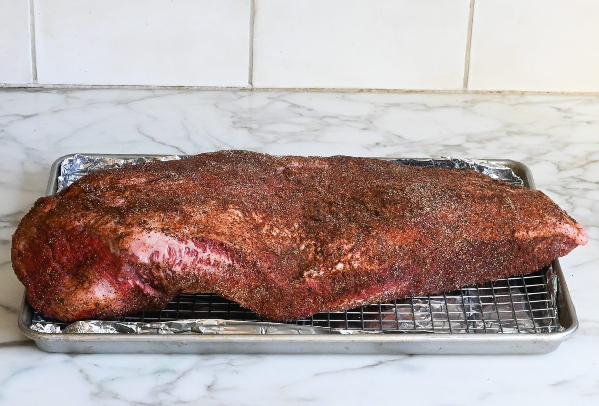 seasoned brisket on rack over baking sheet