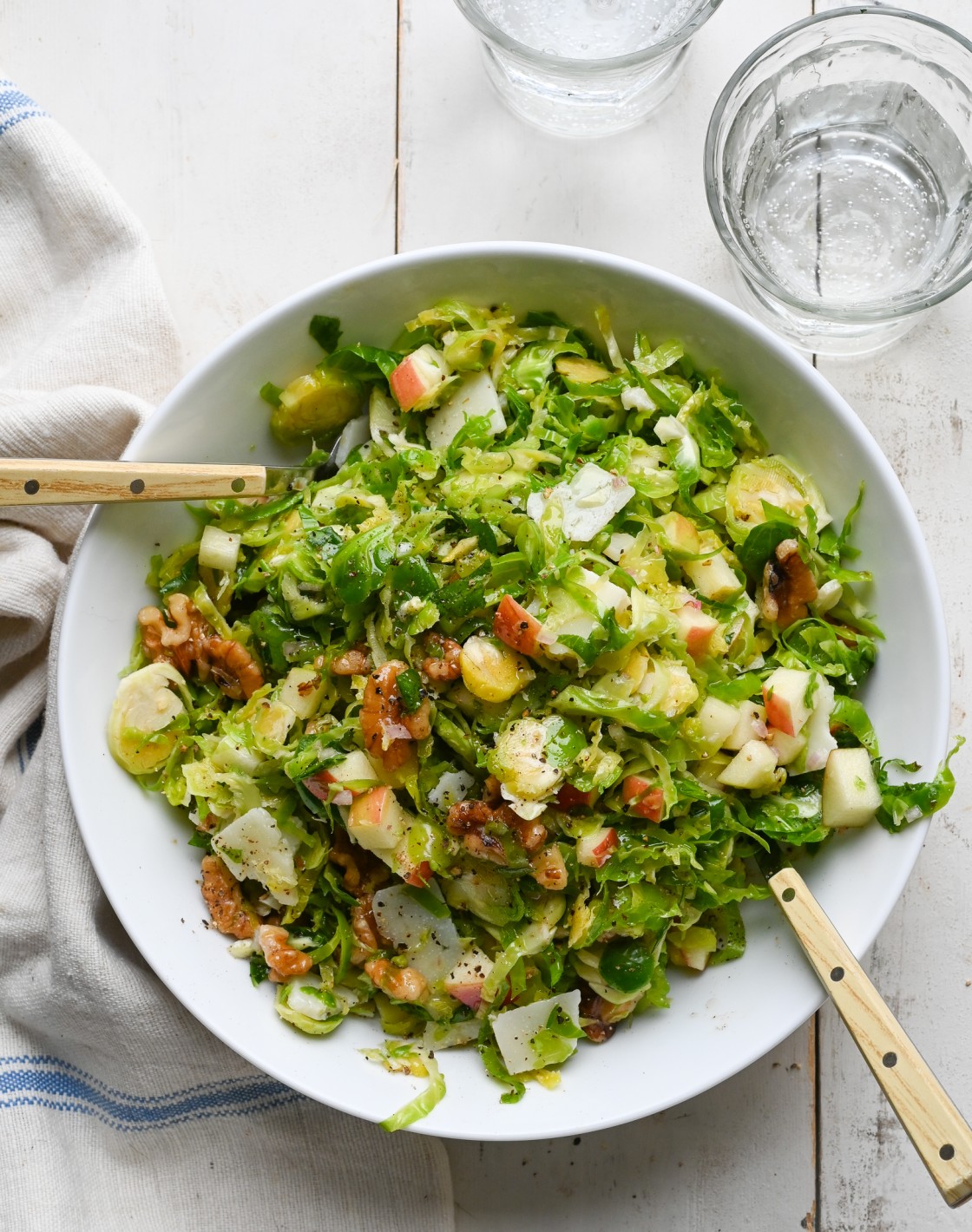 Large bowl of brussels sprout salad with apples, walnuts and parmesan.