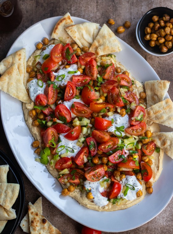 Hummus board with pita, tomatoes, and more.