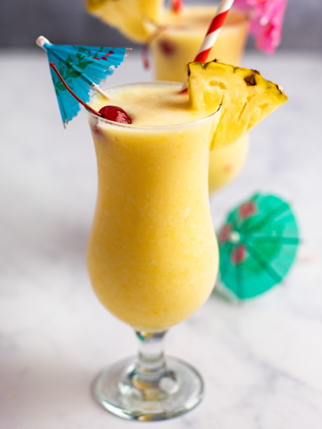 finished pina colada with umbrella, maraschino cherry, and fresh pineapple garnishes