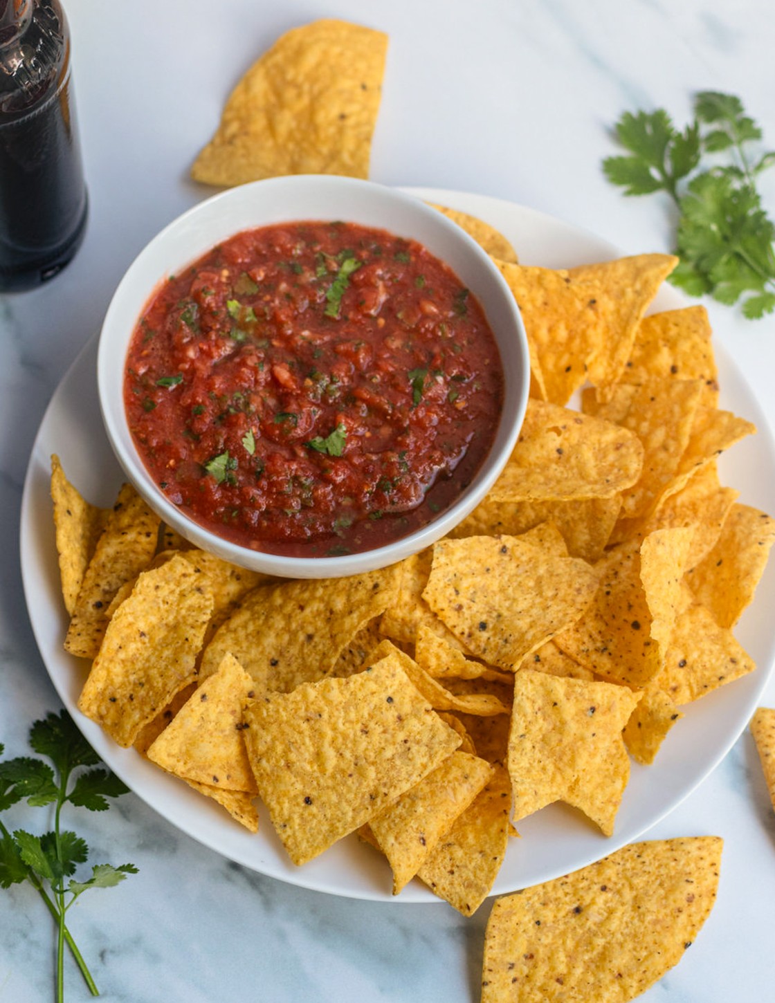 Bowl of salsa on a plate with chips.