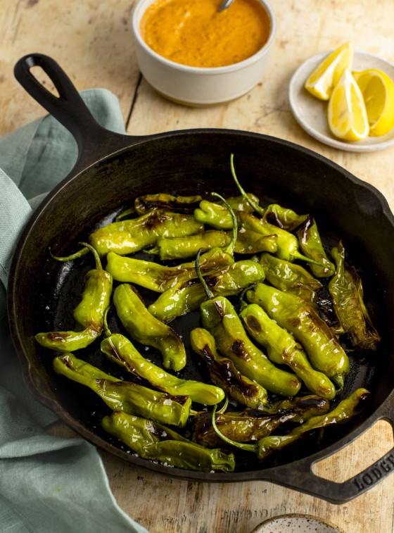 blistered shishito peppers in skillet.