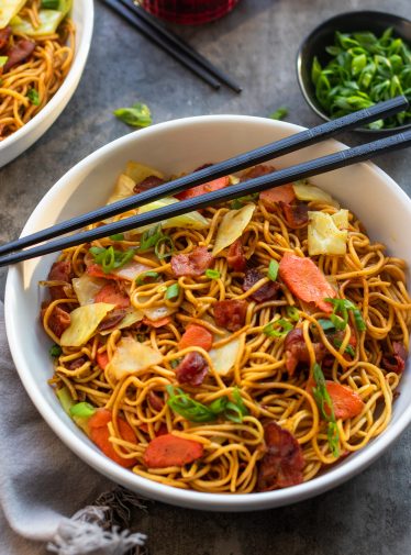 bowl of yakisoba with scallions and chopsticks