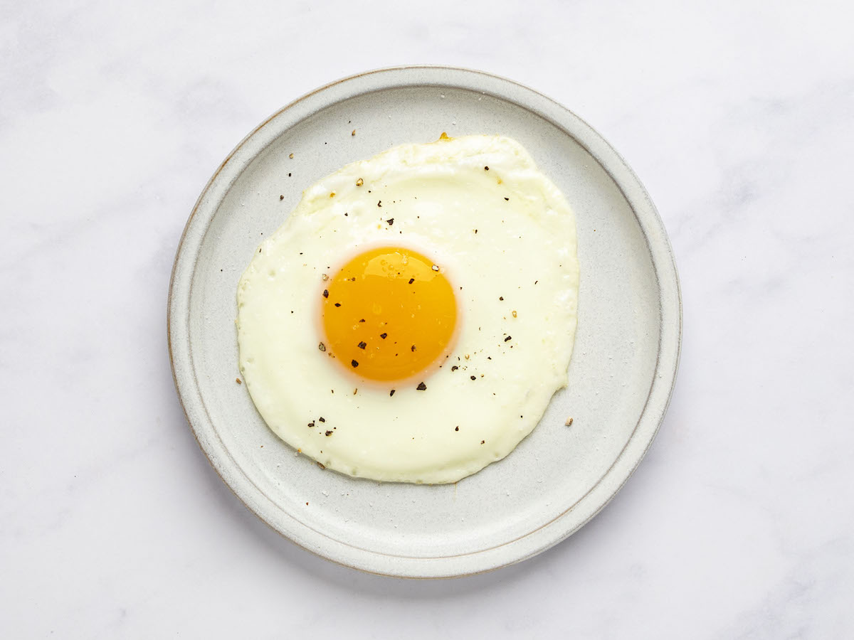 sunny side up egg on white plate with salt and pepper