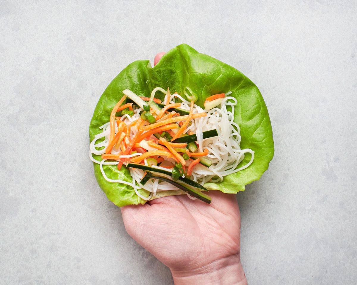 lettuce, noodles, and veggies in hand.