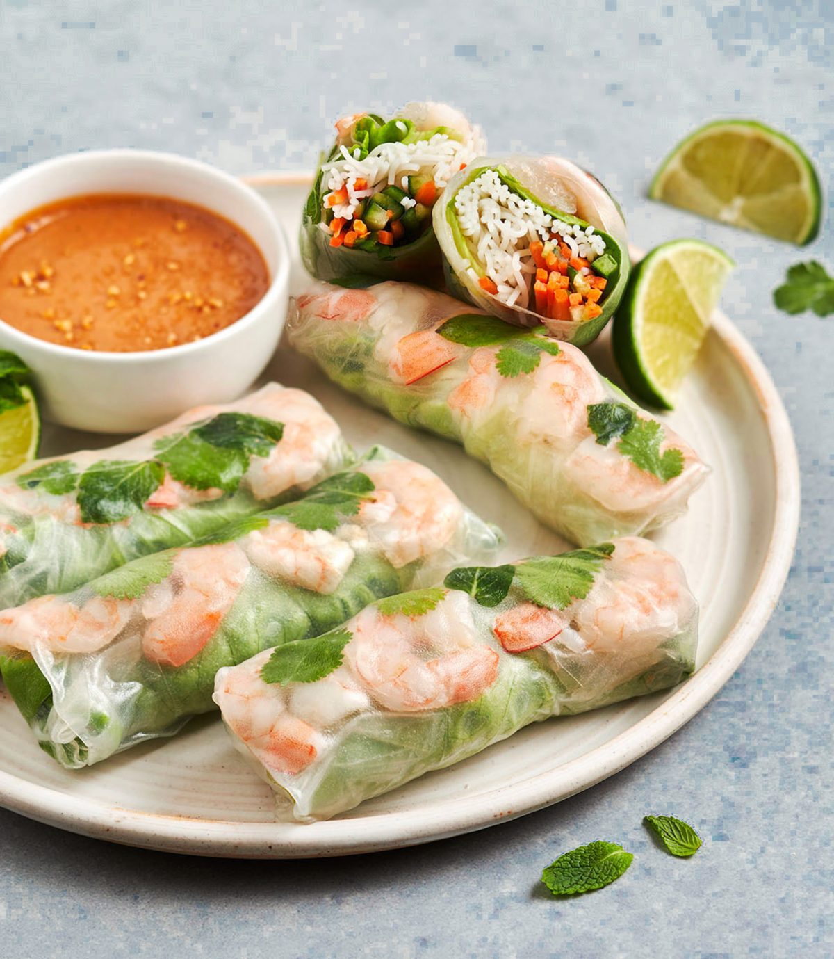 Vietnamese summer rolls on a platter with peanut dipping sauce and limes