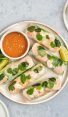 Vietnamese summer rolls on a platter with peanut dipping sauce and limes