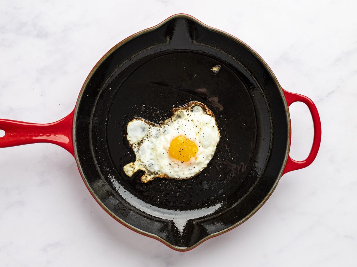 fully cooked egg in cast iron skillet seasoned with salt and pepper