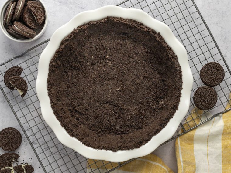 Oreo cookie crust on rack with bowl of oreos and striped napkin.