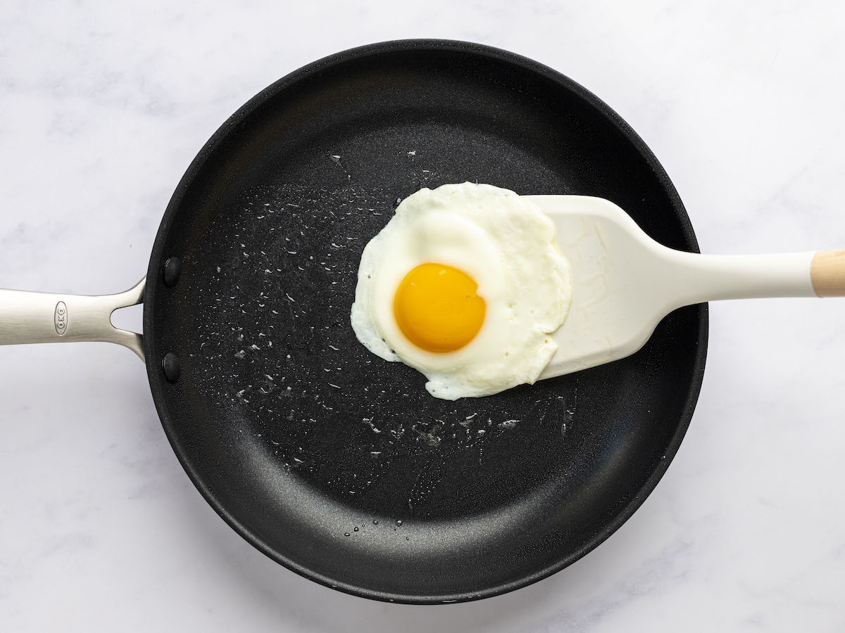 plastic spatula flipping over easy egg in nonstick skillet