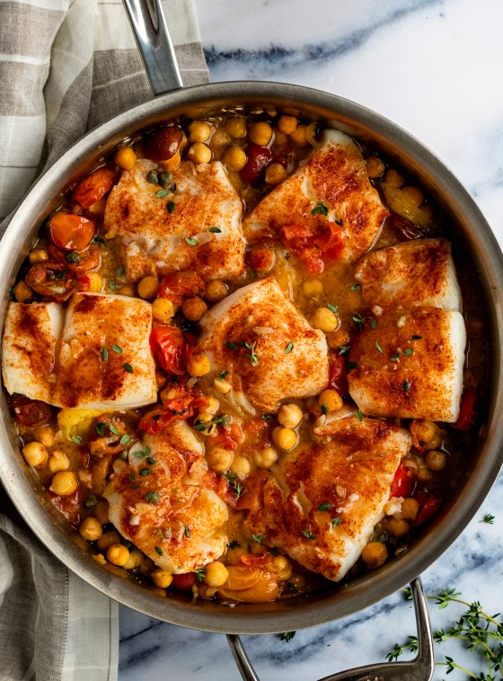 baked cod with tomatoes and chickpeas in skillet with plaid linen napkin