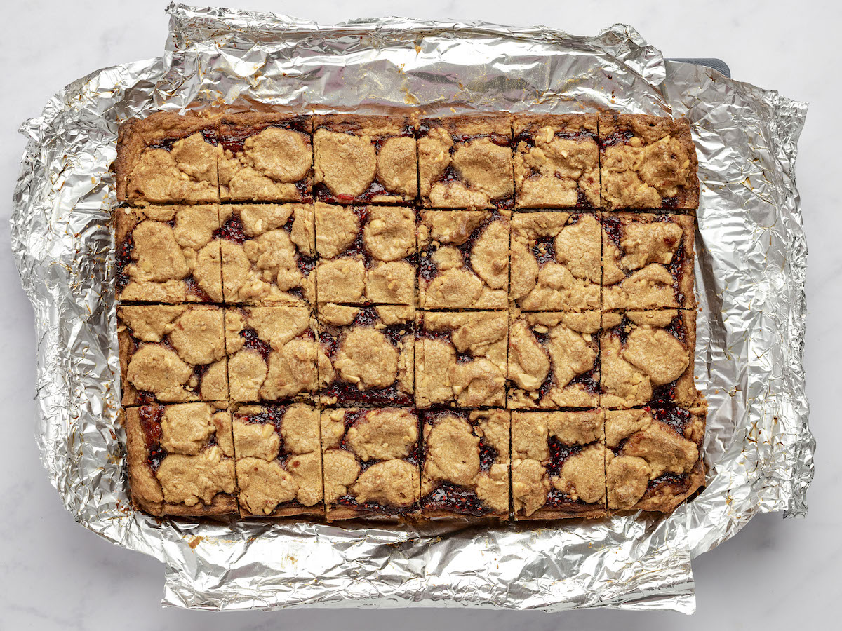 pulling baked PB&J bars out of 9x13-inch pan using foil overhang