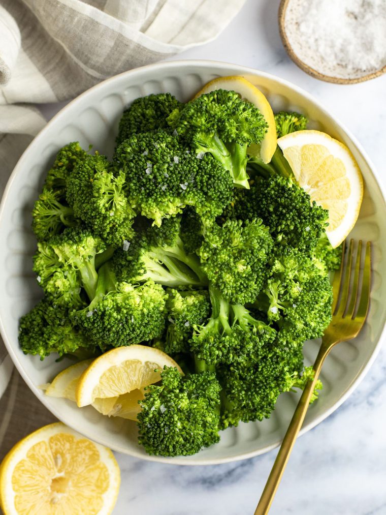 steamed broccoli in bowls with lemon wedges
