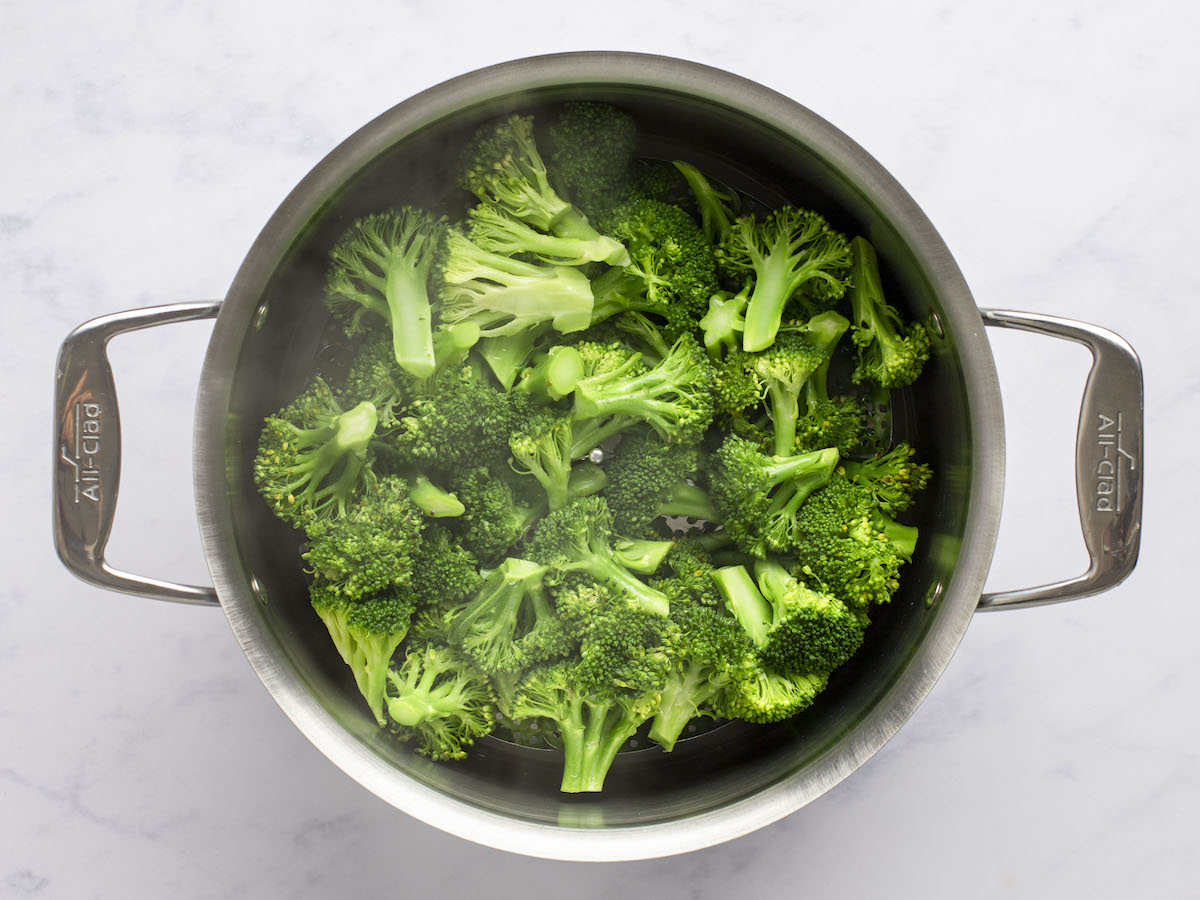 steamed broccoli in steamer basket in large pot