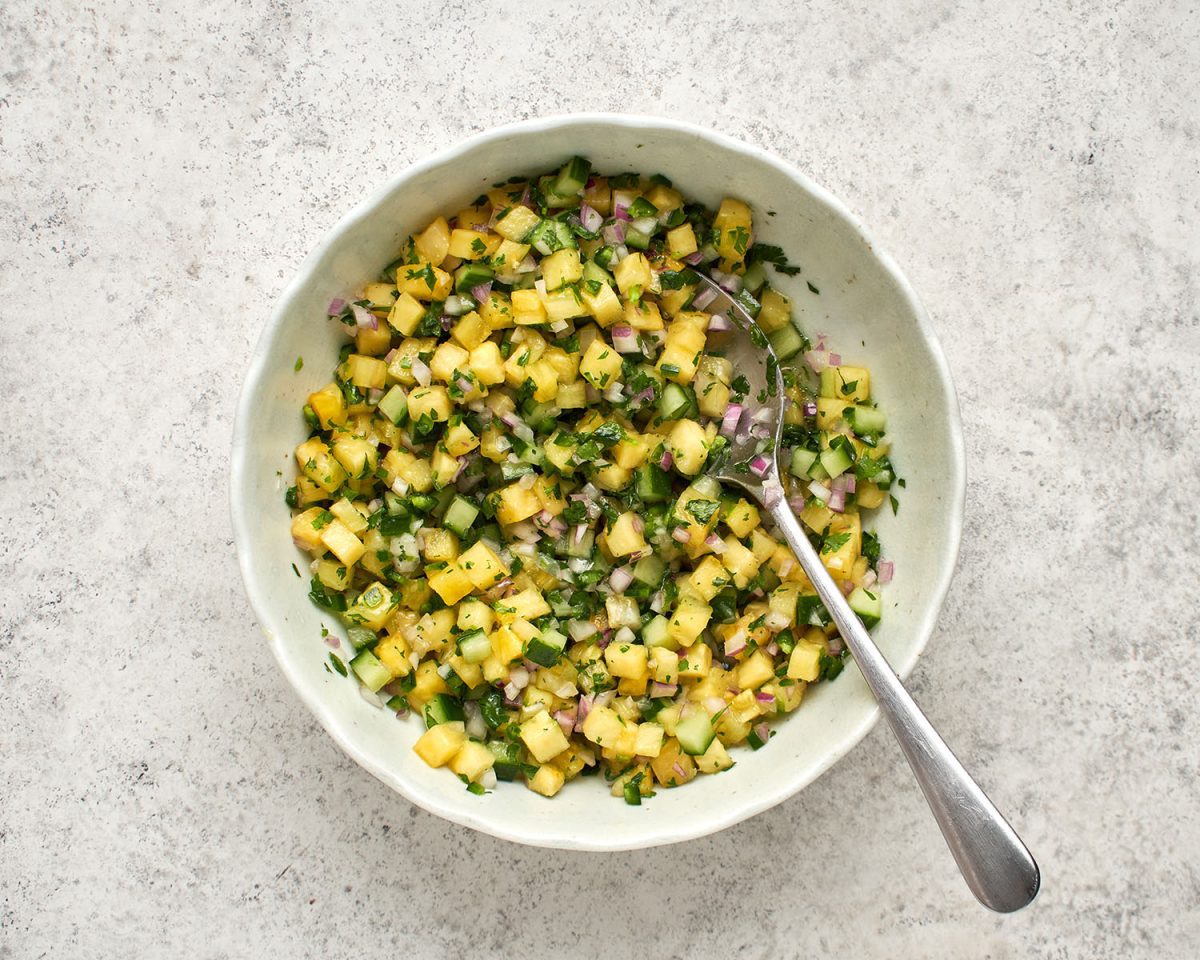 pineapple, lime juice, onion, cucumber, jalapeño pepper, sugar, vegetable oil, salt, and cilantro combined in white bowl