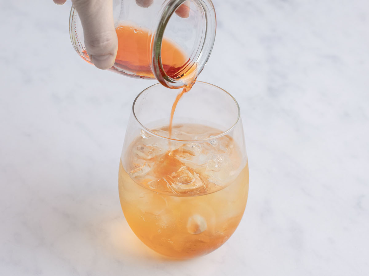 adding aperol into large wine glass with ice cubes and Prosecco 