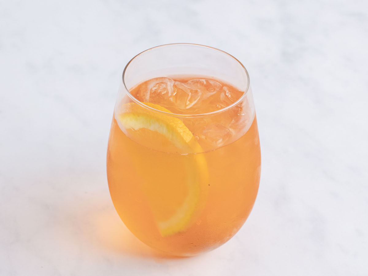 aperol spritz in large wine glass with ice cubes and orange garnish