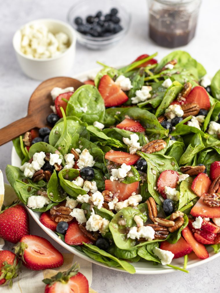 bowl of spinach salad with berries, pecans, goat cheese and raspberry vinaigrette