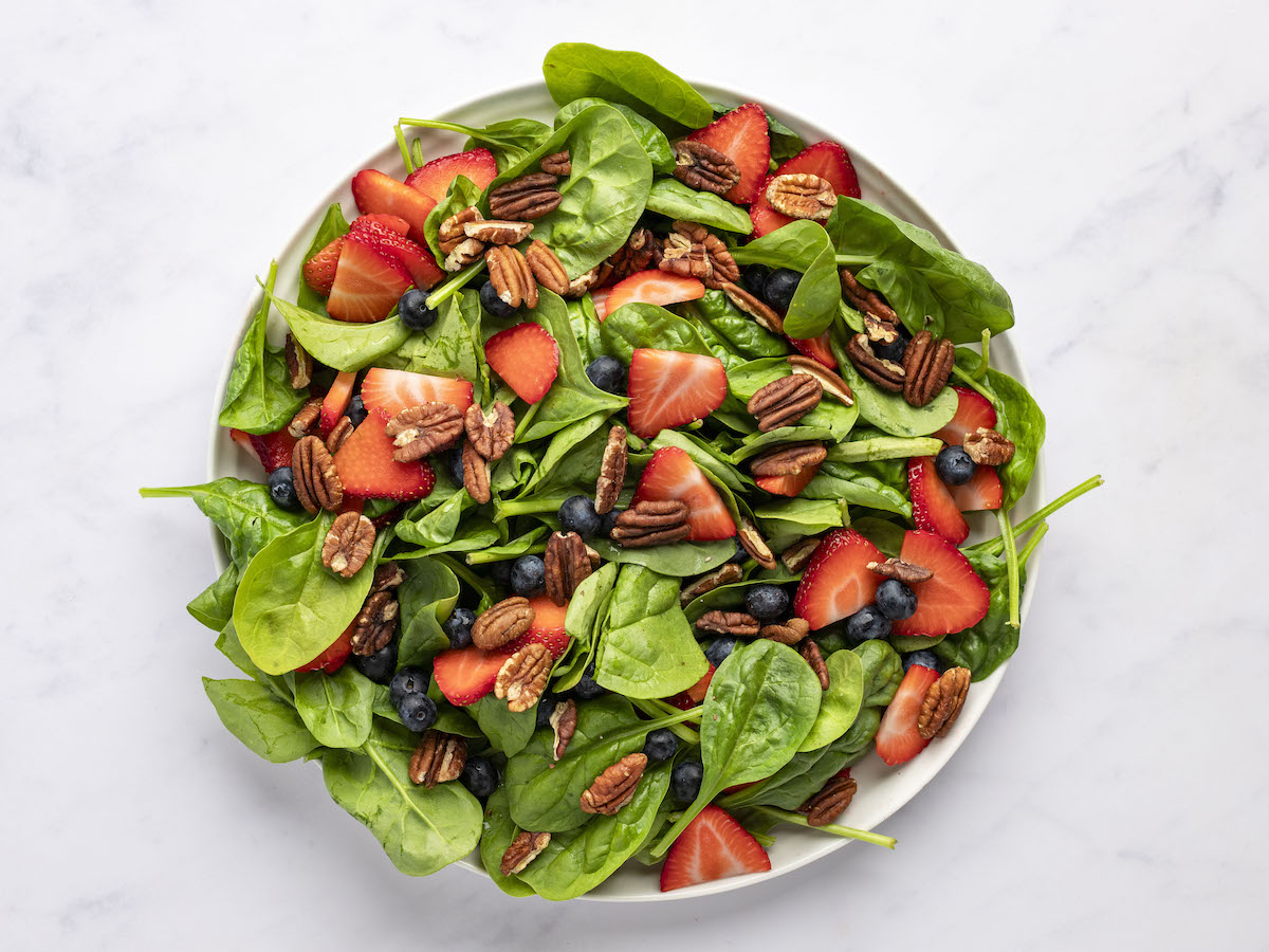 spinach, berries, and pecans in large bowl.