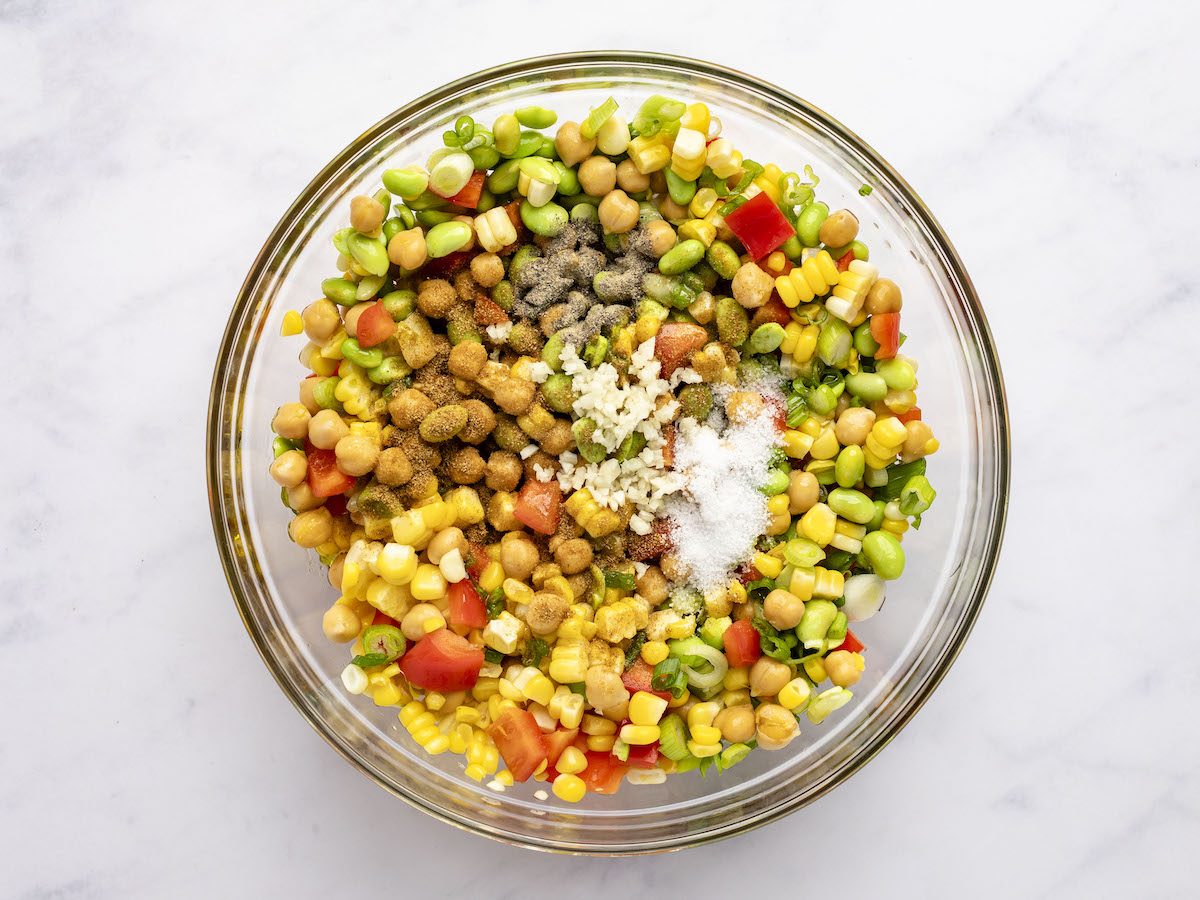 lime juice, garlic, oil, honey, salt, pepper, and cumin added chickpeas, bell pepper, corn, edamame, and scallions in large glass bowl