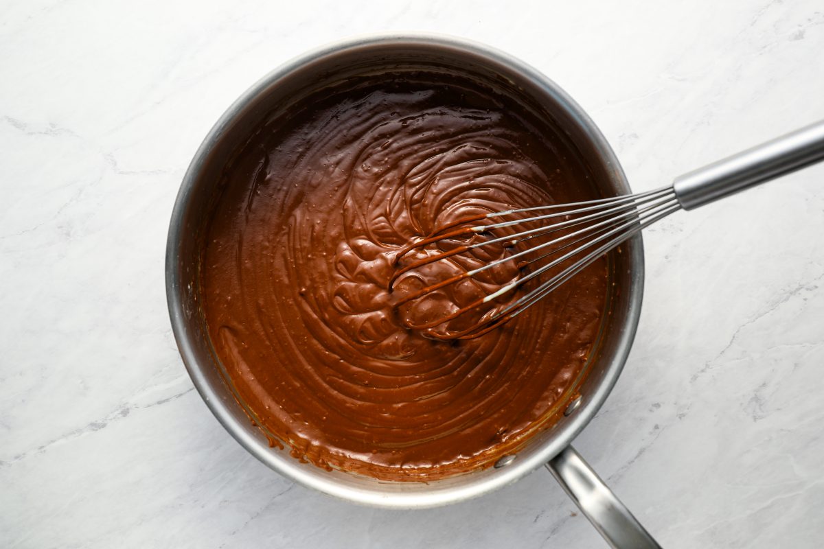 whisking melted chocolate/butter mixture into milk/egg/sugar mixture in saucepan