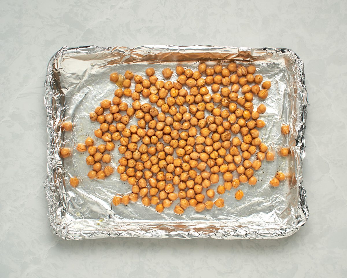 chickpeas tossed with oil, salt, and pepper on foil-lined baking sheet