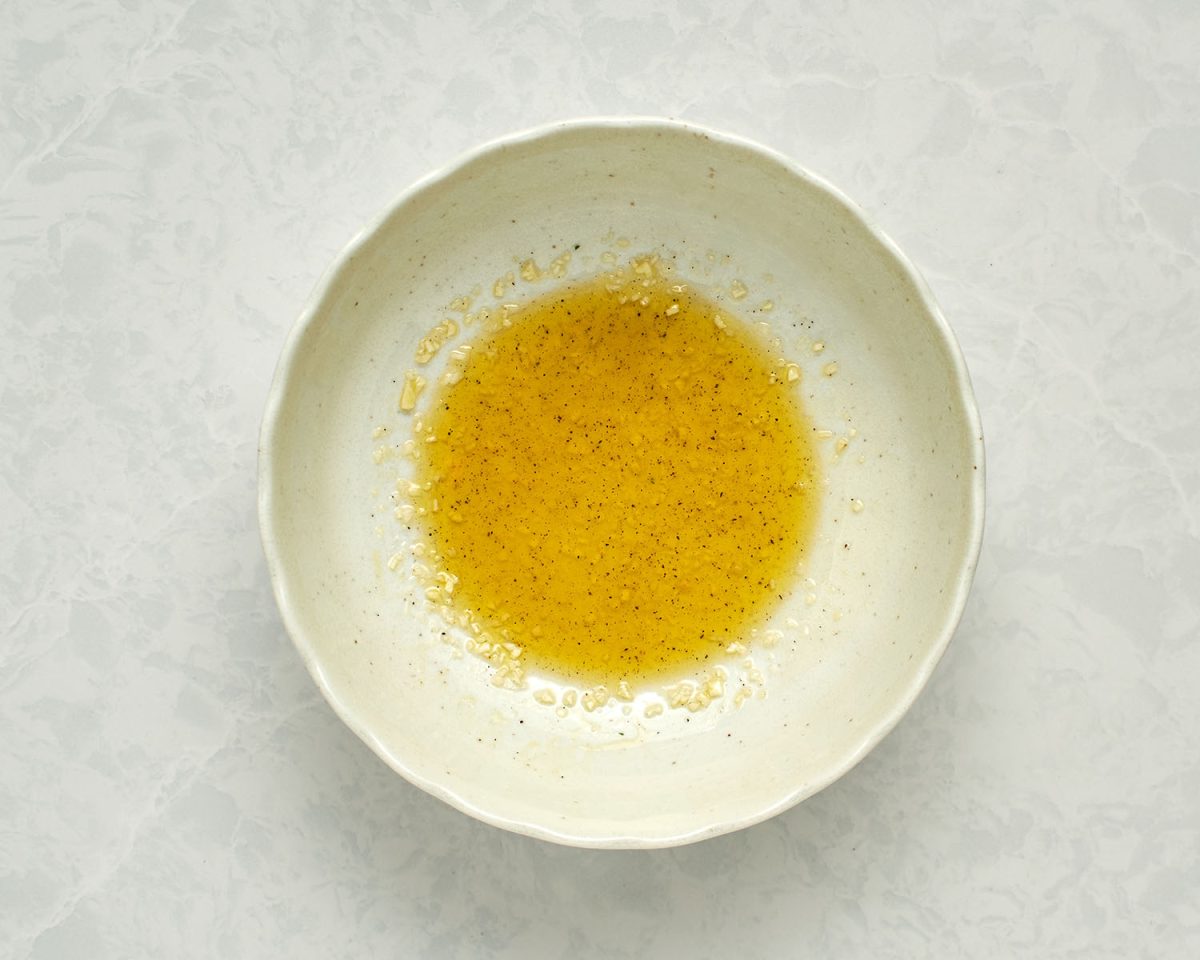 lemon juice, olive oil, garlic, salt, and pepper combined in white bowl