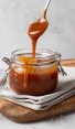 Jar of homemade caramel sauce on wooden board