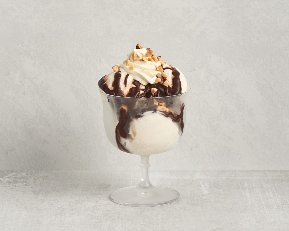 sundae glass with 3 scoops vanilla ice cream, hot fudge, and chopped nuts