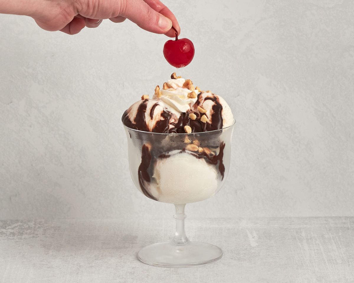 sundae glass with 3 cups vanilla ice cream, hot fudge, chopped nuts and a maraschino cherry