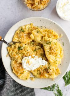 pierogi on plate with sour cream and onions