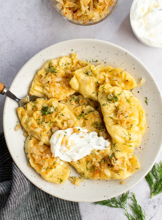 pierogi on plate with sour cream and onions