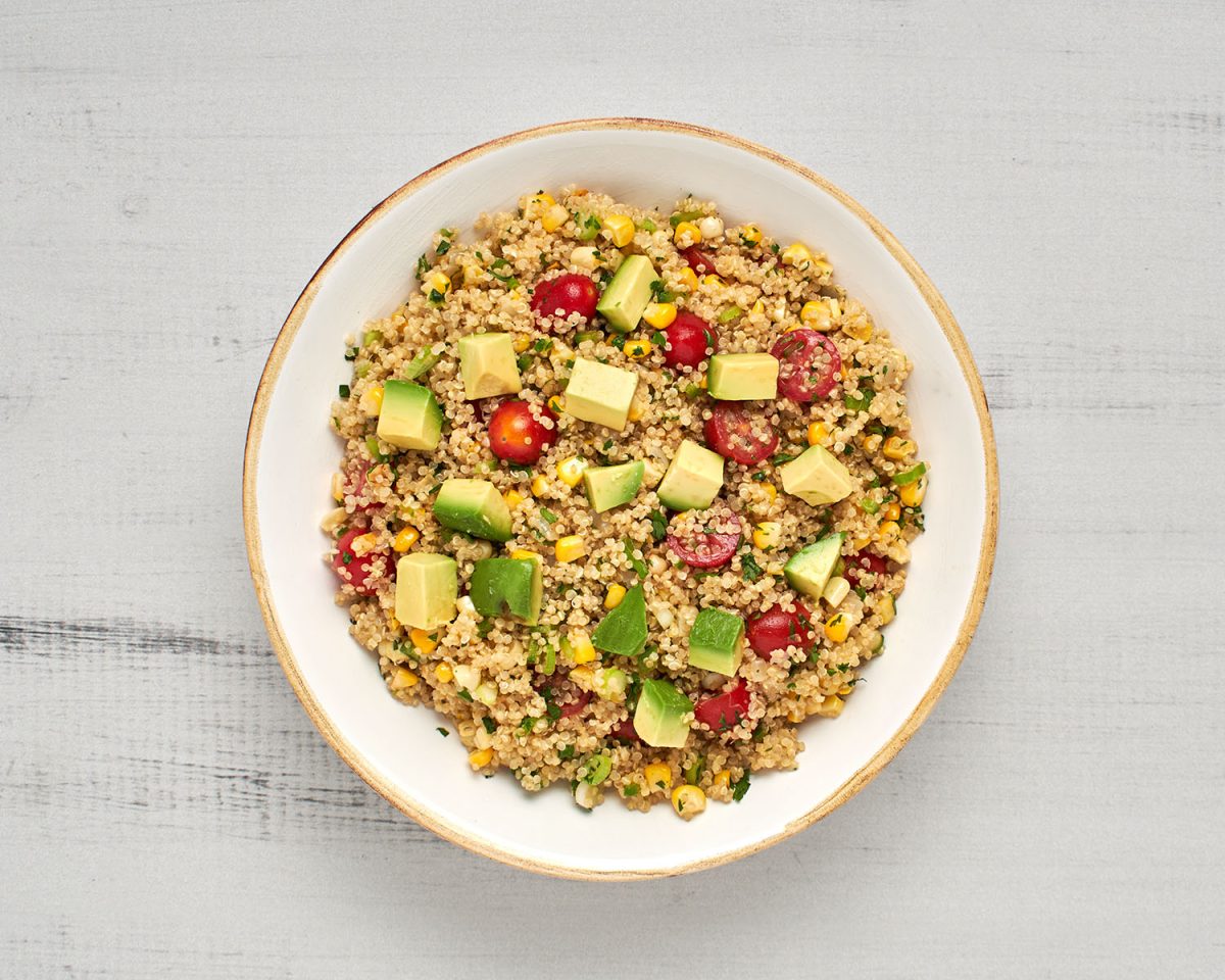 quinoa salad in bowl with diced avocado scattered on top