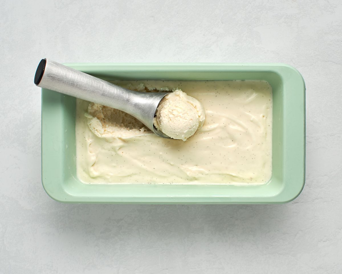 finished vanilla ice cream in green container with ice cream scooper