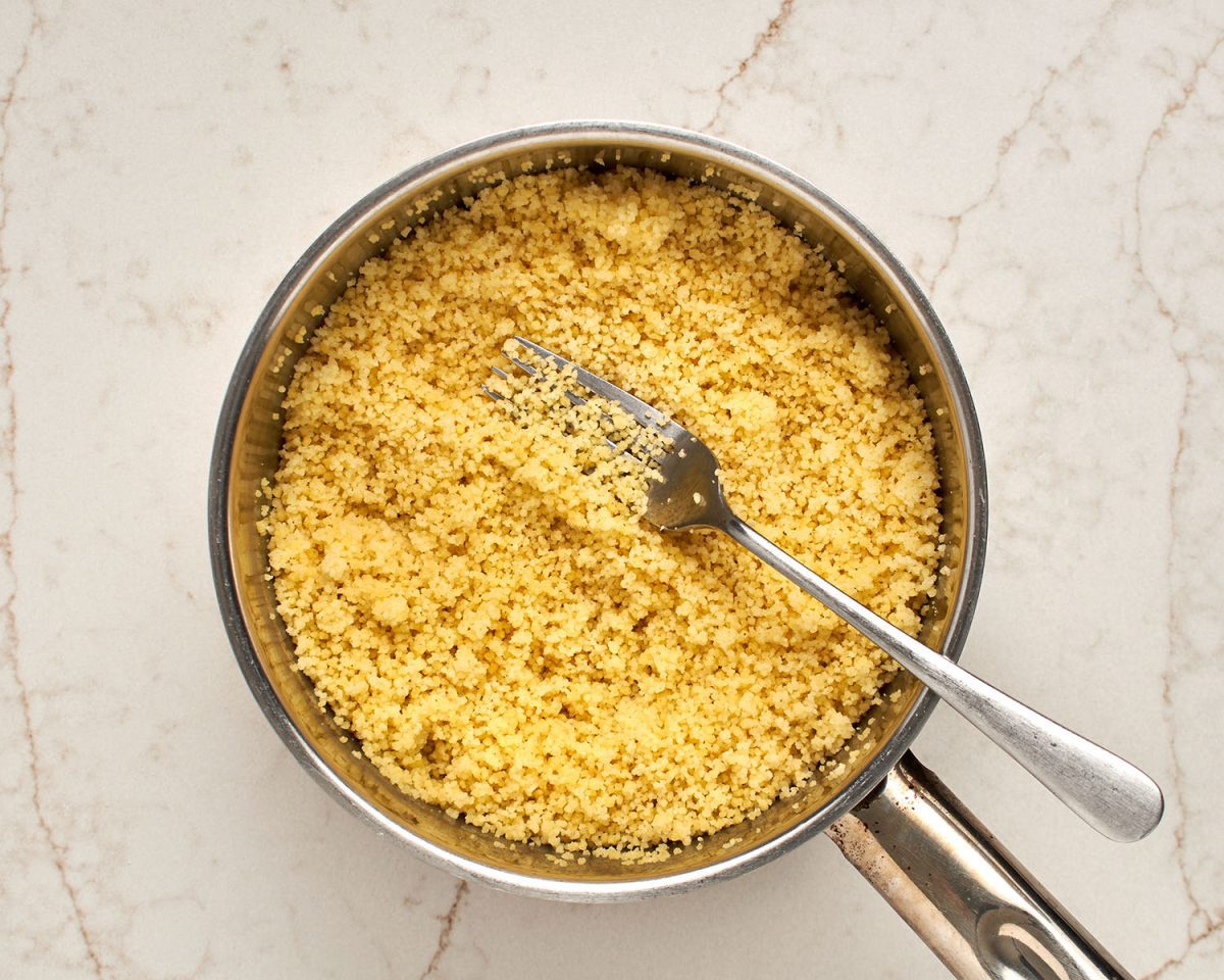 fluffing cooked couscous in medium pot
